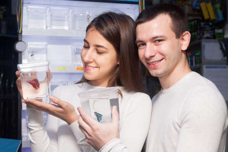 guy and girl smiling and watching aquarium fish in aquariumの写真素材