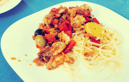 appetizing pasta with vegetables grilled meat and baked egg yolk on a white plateの写真素材