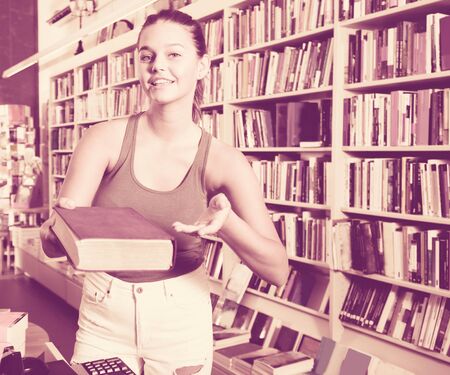 beautiful woman offers a book in a bookstoreの写真素材