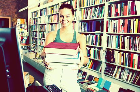 brunete girl chose a lot of books in university library and smilingの写真素材