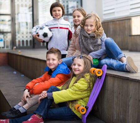 group of smiling children sitting on wooden scaffolding schoolyardの写真素材