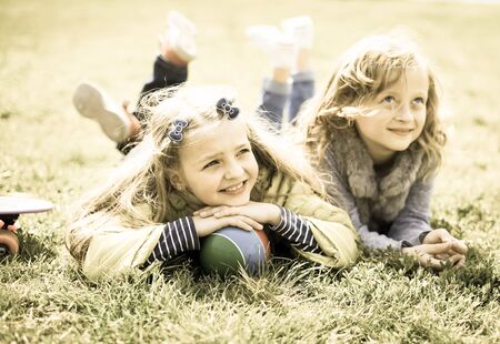 Two blonde girls lie on grassの写真素材