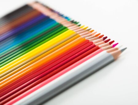 colored pencils lying in row on white backgroundの写真素材