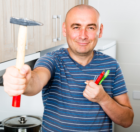 ordinary guy posing with a hammer in his handsの写真素材
