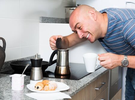 ordinary man in the kitchen preparing coffee in moka potの写真素材