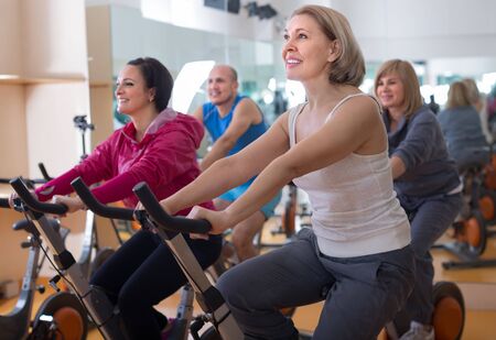 mature females on exercise bikes in the gymの写真素材