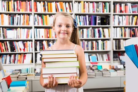 child girl chose a lot of books in the libraryの写真素材