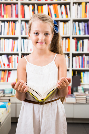 beautiful blonde girl chooses a book in the libraryの写真素材
