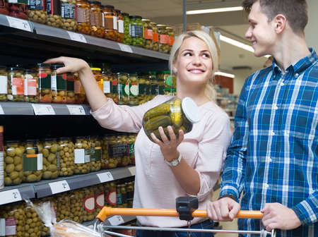 young positive married couple picks pickles at the supermarketの写真素材