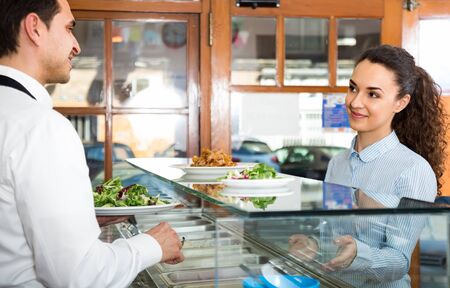 Friendly staff and young woman client at counter of kebab cafeの写真素材