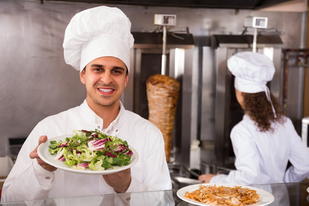 Portrait of friendly male chef with salad plate at fastfood cafeの写真素材