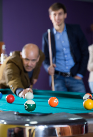 man enthusiastically playing billiards. focus on ballの写真素材