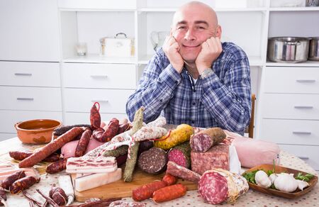 Portrait of ordinary man with lots of meat and sausage productsの写真素材