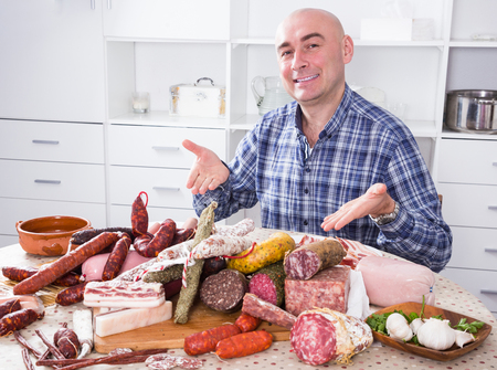 Portrait of ordinary man with lots of meat and sausage productsの写真素材