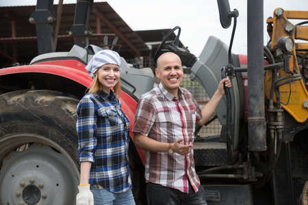 smiling Mature and young farmers posing with old agrimotors in livestock farm. focus on girlの写真素材