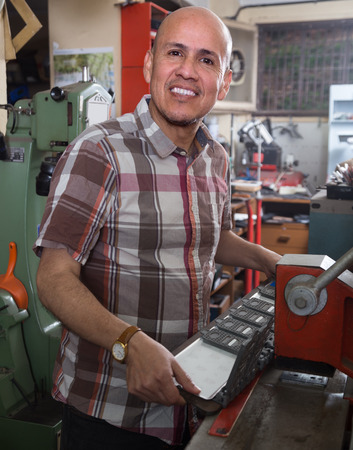 Professional mature worker doing car number plate on printing system latheの写真素材