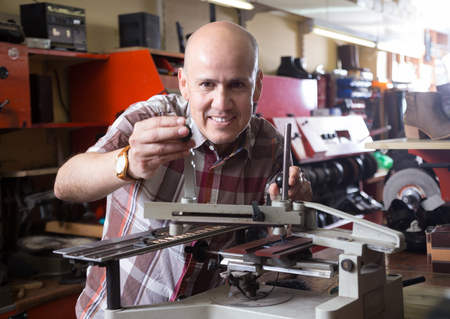 mature Professional worker making mailbox plate on machineの写真素材