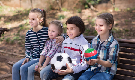 ordinary children with balls in the park on a bench in autumnの写真素材