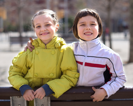 Portrait of nice boy and blonde girl on a bench in the Indian summerの写真素材