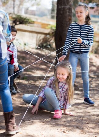 children games. smiling blonde Girl goes through the tangled ropeの写真素材