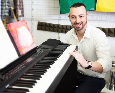 Young customer buying synthesizer in music shop and smilingの写真素材