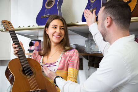 Young couple choosing acoustic guitar in music instruments shopの写真素材