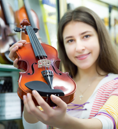 Excited female customer purchasing violins and smilingの写真素材