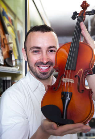 
Male musician selecting classical violin in music instruments studioの写真素材