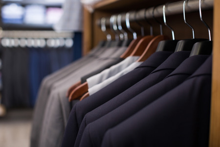 row of male jackets on hangers in men clothing storeの写真素材