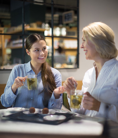 two women with tea and chocolate truffle in cafeの写真素材