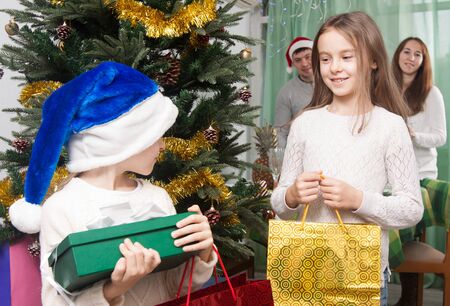 children enjoy gifts near a Christmas tree at homeの写真素材