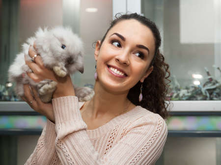 beautiful female customer watching fluffy chinchilla in petshopの写真素材