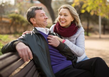 Portrait of Happy elderly couple on a bench in the park in autumn dayの写真素材