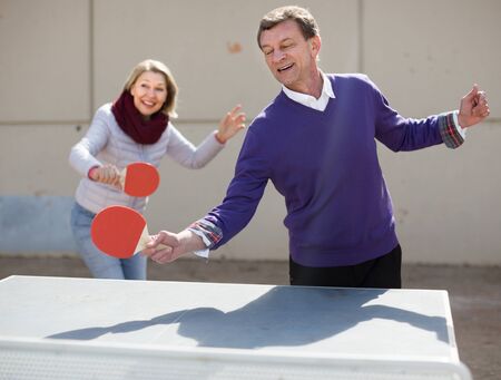 mature family playing table tennis outdoorsの写真素材