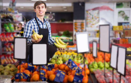 Grocery worker selling seasonal fruits in food marketの写真素材