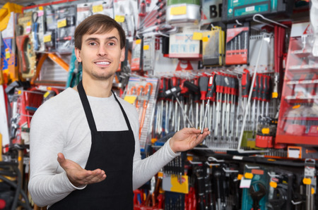 Happy male seller posing at tooling section of household storeの写真素材