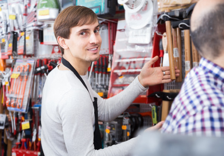 Ordinary seller choosing hammer in household shopの写真素材