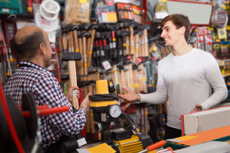young male client and mature salesman at tooling section in building storeの写真素材