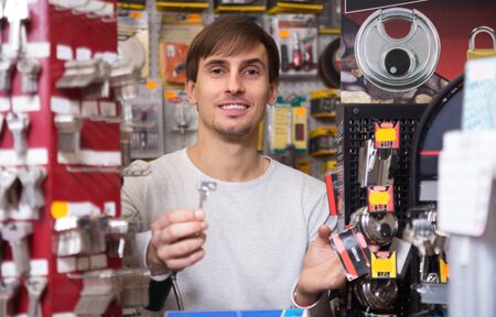 Happy ordinary young handyman making copies of door keys in locksmithの写真素材