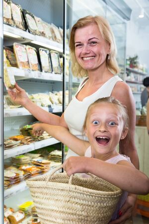young mother with daughter buying chilled foods in supermarketの写真素材