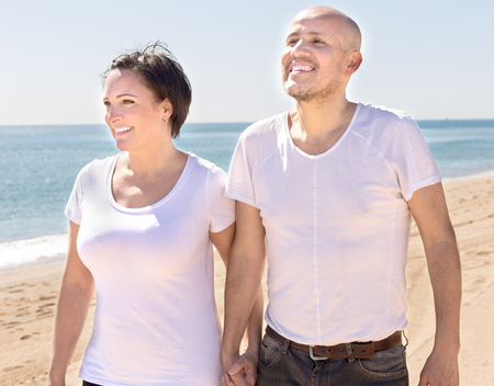 smiling couple of mature man and female walking near seaの写真素材