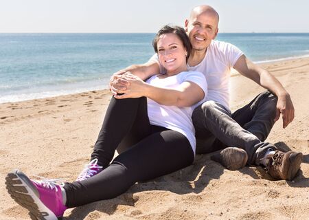 smiling couple of mature man and female sitting near seaの写真素材