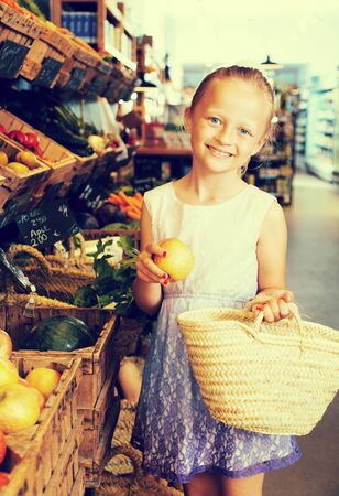 blonde girl choosing apples in vegetable shop. on labels of product names in Catalanの写真素材