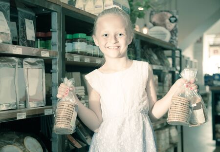 blonde girl posing with cookies in supermarketの写真素材