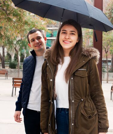 Young couple walking under umbrella at autumn dayの写真素材