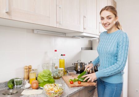 Smiling blonde learning new recipe of vegetables at homeの写真素材