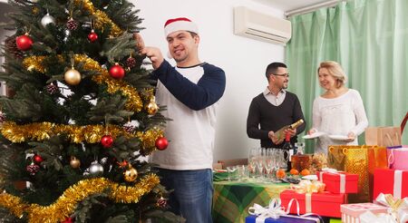 mature couple decorating Christmas tree in home interiorの写真素材