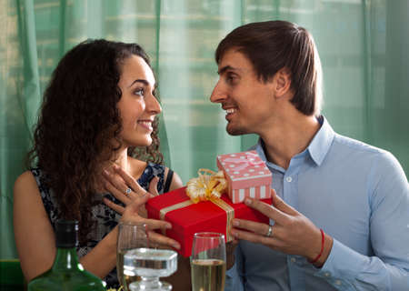 Man giving present to amazed woman during dinner in homeの写真素材