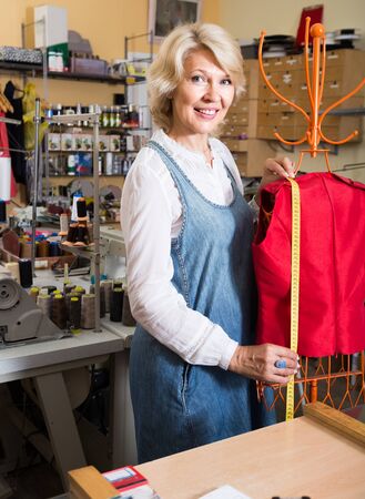 mature Female fashion designer hemming new clothes on mannequinの写真素材