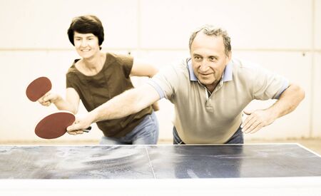 mature couple playing ping pong outdoorsの写真素材
